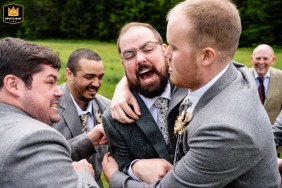 El novio rodeado de sus padrinos de boda, compartiendo un momento alegre mientras se prepara en Lareau Farm Inn en Waitsfield, VT.